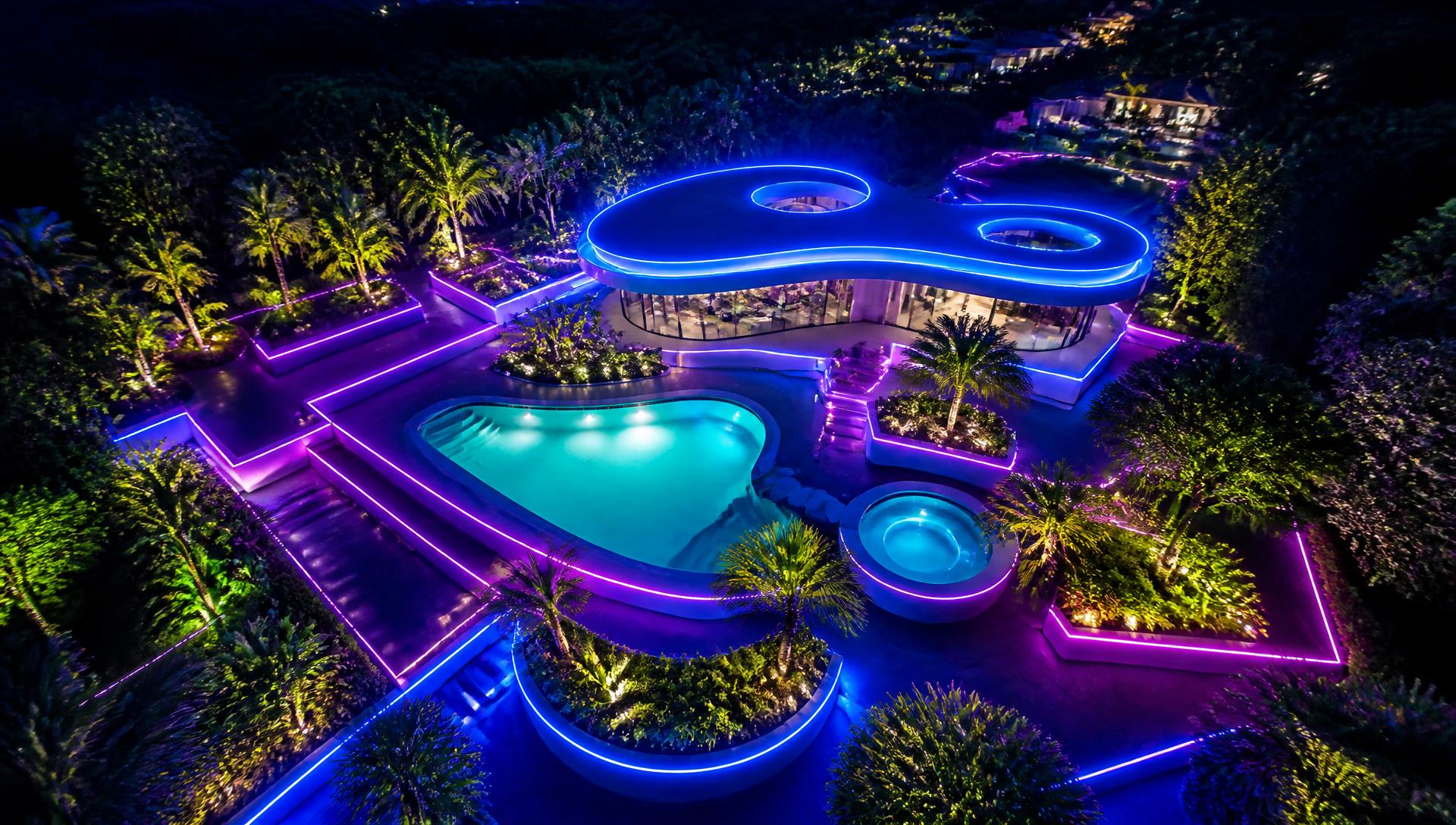 An aerial night view of a futuristic garden layout with glowing geometric paths, an illuminated pool and lit hedges. Images Created by www.future-home.shop